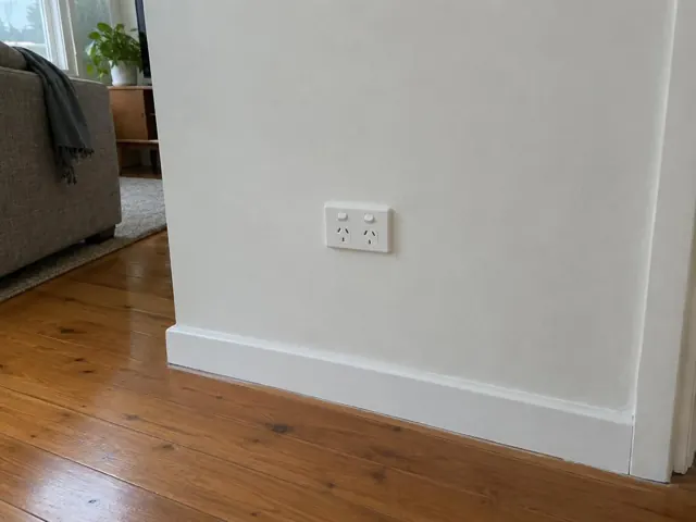 White double power point on a painted wall above timber floorboards in a living room in Green Point