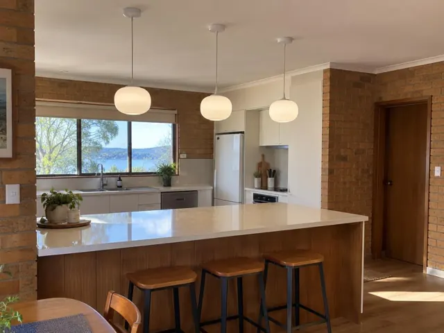 Three pendant lights above a kitchen island in a brick home interior in Kincumber